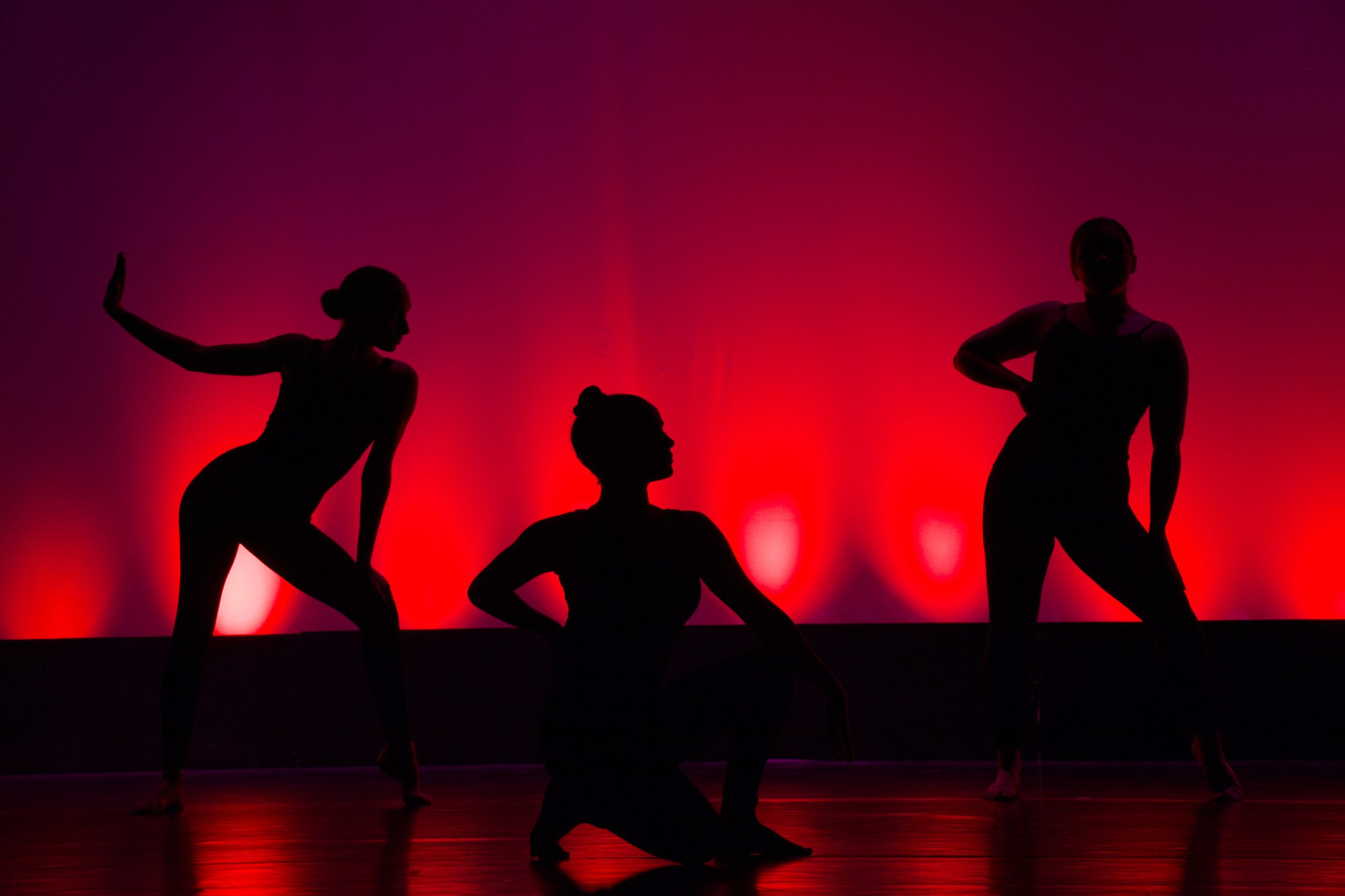 Silhuetas de mulheres dançando com luzes neon ao fundo